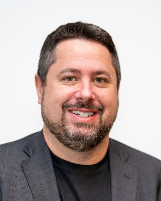 Shawn Snider, smiling, in a dark blazer and t-shirt